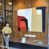 Yelena Revis standing beside her abstract painting Silent Expanse in a gallery exhibition window