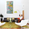 Summer Harmony painting by Yelena Revis styled above a sectional sofa in a modern, sunlit living room interior.